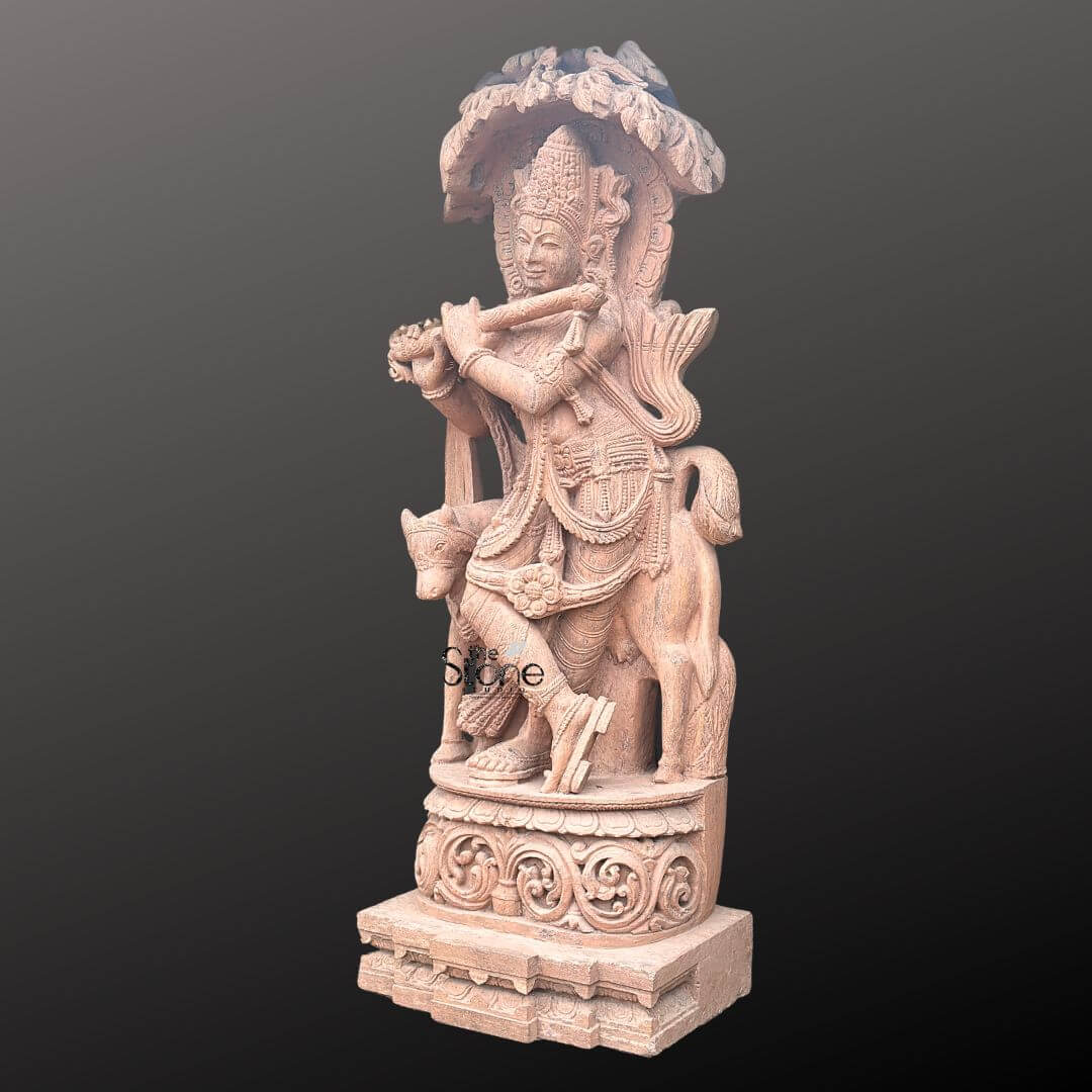 Large Krishna Stone Sculpture with Cow 6ft 4 A majestic 6-foot brown sandstone Lord Krishna Murti specifically designed for a temple setting as highlighted in the accompanying article. The entire sculpture rendered in the rich earthy tones of natural sandstone depicts Lord Krishna in his iconic Tribhanga pose playing his flute with divine grace. His elaborate crown finely detailed frames a serene face with a gentle smile evoking a sense of spiritual tranquility. Krishna is adorned with meticulously carved jewelry including multiple necklaces, armlets and ankle bracelets all skillfully chiseled from the stone. The intricate details extend to Krishna's flowing garments which appear to drape naturally showcasing the masterful craftsmanship. His posture with one leg crossed and the other slightly bent adds to the dynamic elegance of the murti. Standing gently beside Krishna to his left, is a cow a sacred companion symbolizing purity and abundance. The cow's form is also intricately carved with a calm expression further reinforcing Krishna's role as a protector of cows and a benevolent deity. The sculpture stands on a substantial multi-tiered pedestal also carved from sandstone featuring traditional Indian architectural motifs and decorative patterns that enhance its grandeur and stability. Above Krishna an ornate canopy or arch resembling a tree or an artistic temple arch provides a dignified frame adding to the sacred aura of the piece. This 6-foot brown sandstone Lord Krishna murti is a powerful representation of devotion and artistry making it an ideal centerpiece for a temple embodying the spiritual and aesthetic value discussed in the article.