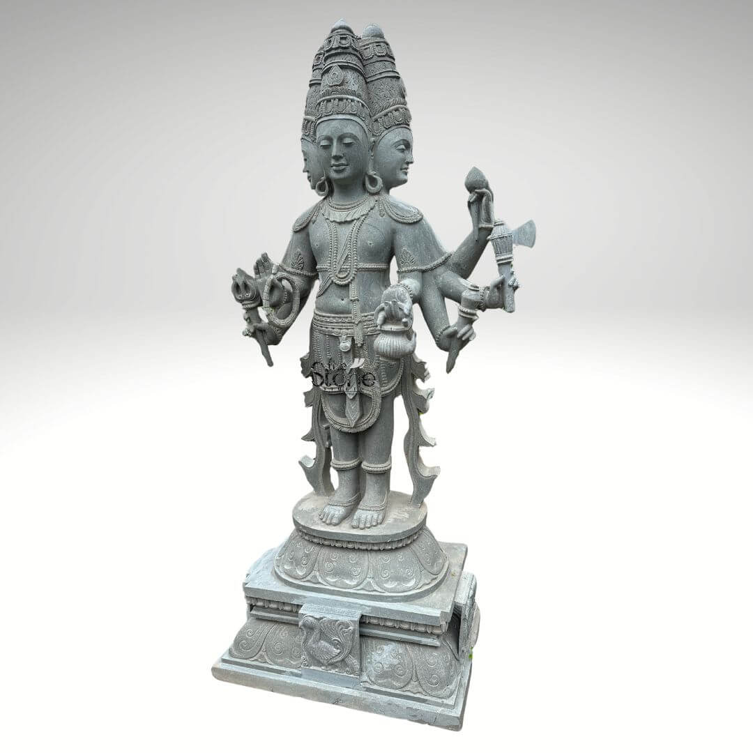 Brahma Stone Statue 7ft 7 A magnificent 7-foot greystone Four-Faced Lord Brahma Statue is presented in a stately front-facing view against a plain light background emphasizing its grandeur and intricate craftsmanship. The statue depicts Lord Brahma the creator god in a standing posture with his characteristic four heads symbolizing his omnipresence and knowledge of the four Vedas. The natural grey tones and subtle textures of the stone lend an ancient and dignified quality to this impressive statue highlighting its detailed carvings. Lord Brahma is meticulously carved with his four serene and contemplative faces each adorned with an elaborate crown and facing the cardinal directions . He is richly adorned with multiple necklaces armlets and a sacred thread all finely detailed. In his multiple hands he holds his traditional attributes including a sruva or rosary a kamandalu and a puskara symbolizing his role in creation and knowledge. His attire is elegantly draped with intricate patterns on his lower garment and decorative elements around his waist. He stands barefoot on a lotus pedestal which in turn rests on a multi-tiered intricately carved base featuring smaller decorative elements and possibly mythical creatures. This 7-foot greystone Four-Faced Lord Brahma Statue is a profound representation of creation wisdom and cosmic knowledge making it a powerful and auspicious addition to any temple or significant spiritual space. The exceptional craftsmanship in natural greystone not only makes it a visually striking piece but also imbues it with deep cultural and religious significance. This exquisitely detailed statue serves as a commanding focal point for devotion and prayer radiating positive energy and ancient wisdom to all who venerate it.