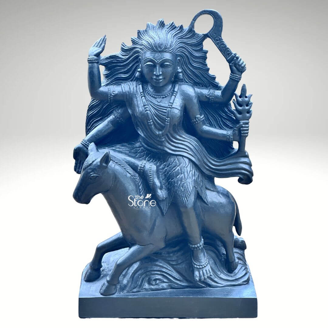 Black Stone Kaalratri Statue 15" 4 A powerful Kaalratri Mata statue carved from black stone is dynamically posed and presented against a clean white background. This fierce manifestation of the Divine Mother one of the Navadurga is depicted riding a horse symbolizing her swiftness and power in overcoming malevolence. Her hair appears unbound and flows dramatically upwards and outwards emphasizing her formidable and untamed nature which aligns with her name meaning the night of blackness. The black stone Kaalratri Mata statue is rich with symbolic and intricate details. The goddess is multi-armed with her hands wielding various weapons and ritual implements; one hand prominently holds a saber or sword-like weapon aloft, while another grasps a trident or a similar fiery object signifying her destructive power against evil. Her expression though intense conveys a sense of divine purpose and protective energy. She is adorned with sculpted jewelry including necklaces and bangles which stand out against her dark form. The horse she rides is captured mid-stride its legs seemingly galloping through stylized waves or clouds carved to enhance the sense of movement and raw power. The deep uniform black of the stone enhances the statue's dramatic and revered presence. This striking black stone Kaalratri Mata statue is an excellent visual for an article detailing such powerful deities. The choice of black stone perfectly embodies her dark transformative aspect while the intricate carving of her wild hair weapons and dynamic pose on the horse conveys her relentless energy. The statue is a compelling representation of Kaalratri Mata's role in vanquishing fear ignorance and negativity making it a significant piece for devotees and art enthusiasts seeking to understand her divine might and incorporate her protective presence in their devotion.