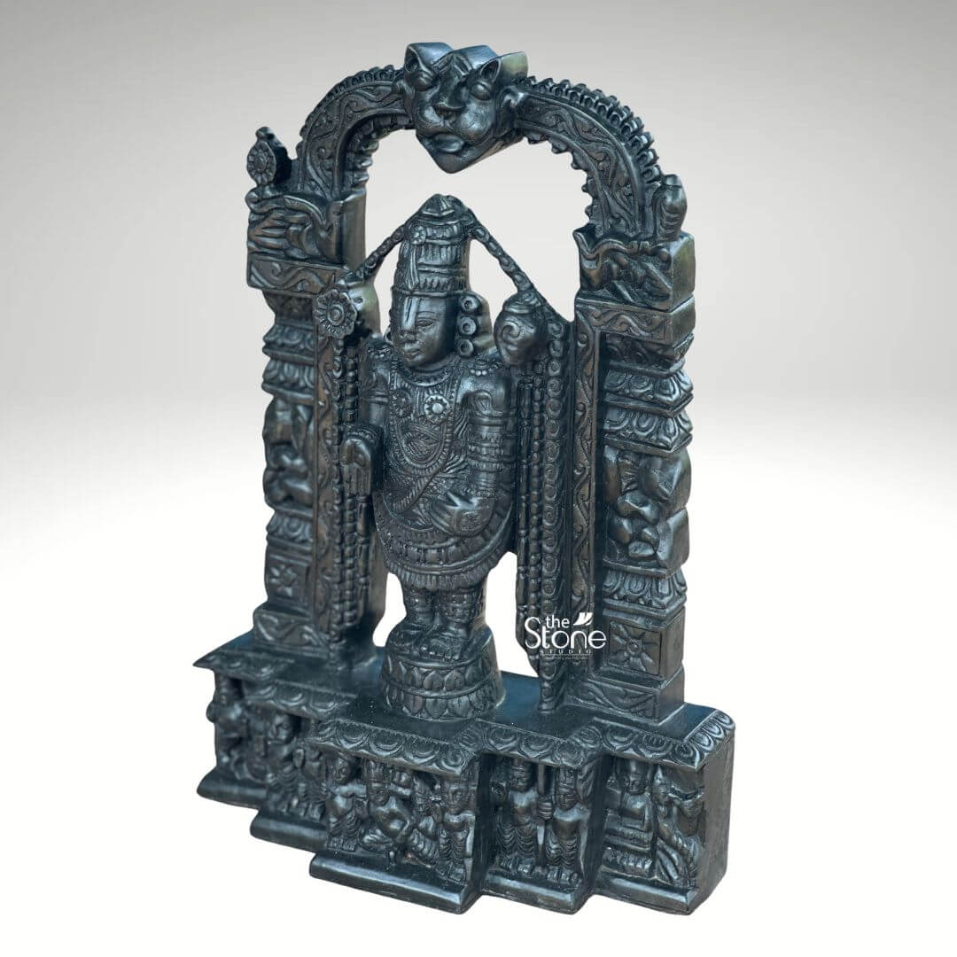Tirupati Balaji Statue in Black Stone 18" 4 An exquisite 18-inch Lord Venkateswara Swamy stone idol meticulously carved from black stone and framed by an ornate temple arch is presented against a plain light background. This stunning Balaji black stone statue captures Lord Venkateswara in his iconic standing posture emanating an aura of divine grace and profound power. The deep polished surface of the black stone provides a dramatic contrast enhancing the intricate details of the sculpture and its elaborate architectural setting making it a perfect piece for a home temple or a significant spiritual collection. Lord Venkateswara Swamy is depicted with his characteristic features including the prominent Urdhva Pundra on his forehead a majestic crown and various traditional ornaments such as multiple necklaces armlets and a sacred thread all finely detailed. His right hand is raised in the Abhaya Mudra offering blessings and reassurance to devotees while his left hand rests on his thigh symbolizing protection and prosperity. He stands on a lotus pedestal which is integrated into a multi-tiered base adorned with smaller figures and decorative carvings including devotees and mythological scenes all contributing to the grandeur of the piece. The intricate temple archway above him is equally detailed featuring divine figures floral motifs and a Kirtimukha at the apex. This 18-inch black stone Lord Venkateswara Swamy idol with its integrated temple arch is a profound representation of the preserver of the universe. The exceptional craftsmanship in black stone not only makes it a visually striking piece but also embodies deep cultural and religious significance offering a powerful focal point for devotion and prayer. The rich detailing of the deity and his surrounding archway reflects centuries of tradition making it a truly remarkable and revered artifact that brings blessings and a spiritual presence into any sacred space fostering a sense of divine connection.