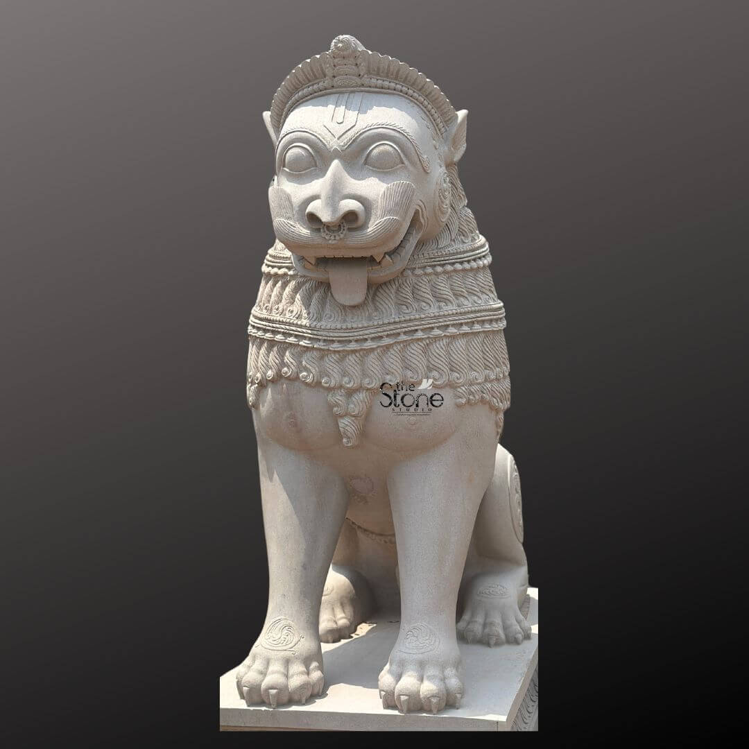 Traditional Stone Temple Lion Statue 7ft 7 A magnificent 7-foot Stone Lion Statue intricately carved from off-white sandstone is presented in a stately front-facing view against a dark plain background emphasizing its grandeur and commanding presence perfectly suited for a temple gate. The statue depicts a powerful lion in a seated alert posture its facial features stylized and adorned embodying strength guardianship and divine authority making it an iconic and protective figure for sacred entrances. The light natural hue of the sandstone allows the elaborate carvings to stand out vividly. The lion's face is central to the image featuring prominent watchful eyes a broad snout, and an open mouth with a tongue extended conveying a sense of ferocity and protective power. Its mane is intricately carved with layers of textured patterns and decorative bands extending to its powerful chest. The body is robust and muscular with traditional swirling motifs and other embellishments visible on its legs and shoulders. Its large paws are firmly planted indicating stability and strength. The entire sculpture rests upon a robust multi-tiered base also adorned with intricate patterns providing a solid foundation and enhancing its imposing presence at a temple gate. This 7-foot off-white sandstone Stone Lion Statue is a profound representation of power protection and divine authority making it an ideal guardian for a temple gate. The exceptional craftsmanship in sandstone not only makes it a visually striking piece but also imbues it with deep cultural and religious significance. This exquisitely detailed statue serves as a commanding sentinel radiating strength and an ancient spiritual presence embodying centuries of artistic tradition and architectural grandeur within Hindu temples.