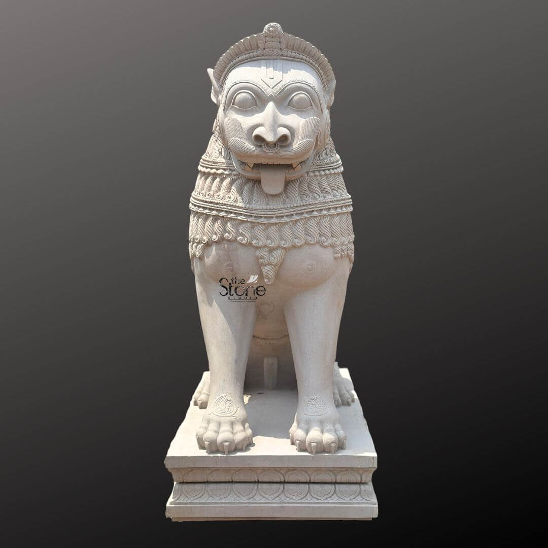 Traditional Stone Temple Lion Statue 7ft 9 A magnificent 7-foot Temple Entrance Lion Statue intricately carved from off-white sandstone is presented in a stately front-facing view against a dark plain background emphasizing its grandeur and commanding presence. The statue depicts a powerful lion in a seated alert posture its facial features stylized and adorned embodying strength guardianship and divine authority making it an iconic and protective figure for sacred entrances. The light natural hue of the sandstone allows the elaborate carvings to stand out vividly. The lion's face is central to the image featuring prominent watchful eyes a broad snout, and an open mouth with a tongue extended conveying a sense of ferocity and protective power. Its mane is intricately carved with layers of textured patterns and decorative bands extending to its powerful chest. The body is robust and muscular with traditional swirling motifs and other embellishments visible on its legs and shoulders. Its large paws are firmly planted indicating stability and strength. The entire sculpture rests upon a robust multi-tiered base also adorned with intricate pattern providing a solid foundation and enhancing its imposing presence at a temple entrance. This 7-foot off-white sandstone Temple Entrance Lion Statue is a profound representation of power, protection, and divine authority making it an ideal guardian for a temple entrance. The exceptional craftsmanship in sandstone not only makes it a visually striking piece but also imbues it with deep cultural and religious significance. This exquisitely detailed statue serves as a commanding sentinel radiating strength and an ancient spiritual presence embodying centuries of artistic tradition and architectural grandeur within Hindu temples.