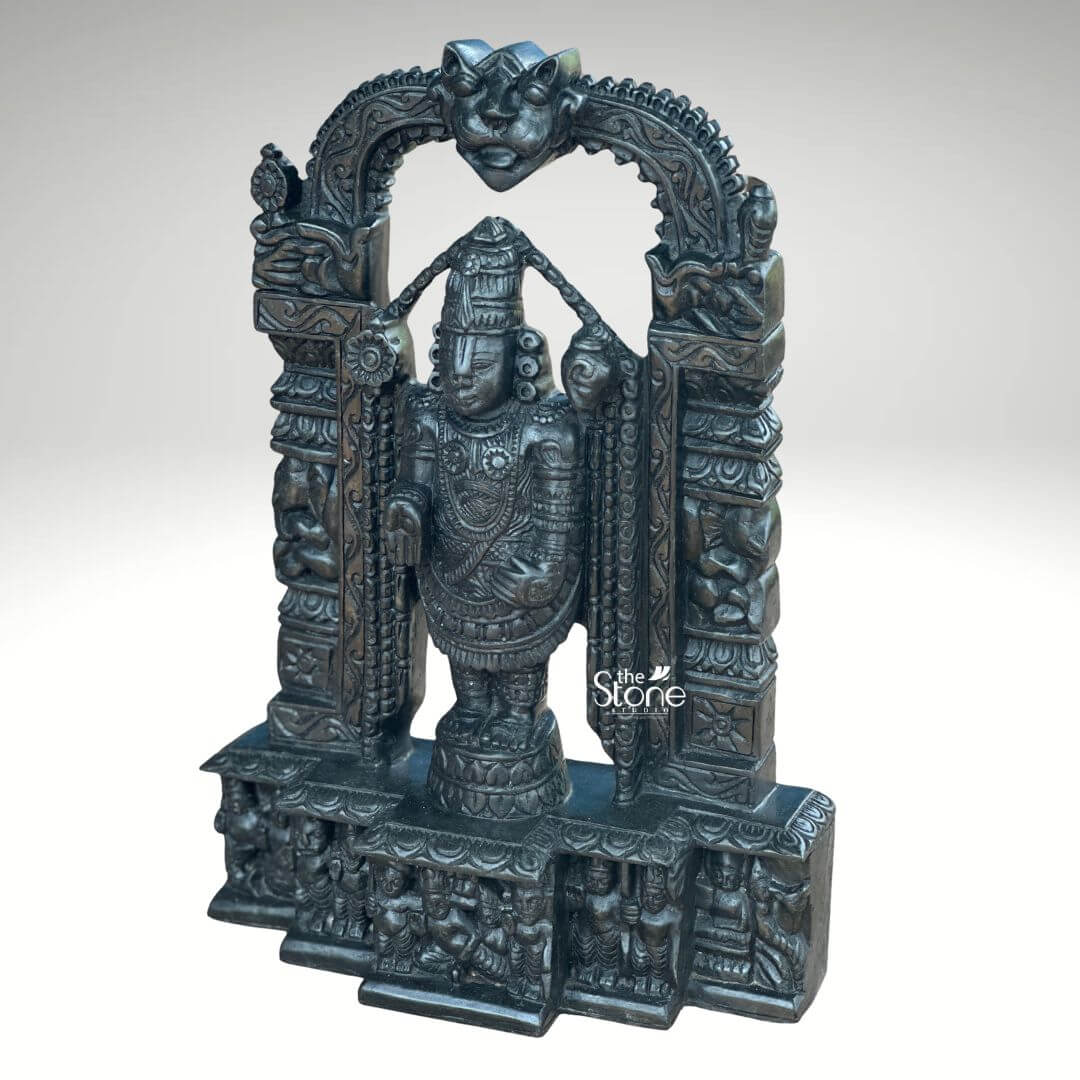 Tirupati Balaji Statue in Black Stone 18" 6 An exquisite 18-inch Tirupati Balaji Murti meticulously carved from black stone and framed by an ornate temple arch is presented against a plain light background making it an ideal piece for a pooja room. This stunning Balaji black stone statue captures Lord Venkateswara in his iconic standing posture emanating an aura of divine grace and profound power. The deep polished surface of the black stone provides a dramatic contrast enhancing the intricate details of the sculpture and its elaborate architectural setting perfect for devotional practices. Lord Balaji is depicted with his characteristic features including the prominent Urdhva Pundra on his forehead a majestic crown and various traditional ornaments such as multiple necklaces armlets and a sacred thread all finely detailed. His right hand is raised in the Abhaya Mudra offering blessings and reassurance to devotees while his left hand rests on his thigh symbolizing protection and prosperity. He stands on a lotus pedestal which is integrated into a multi-tiered base adorned with smaller figures and decorative carvings including devotees and mythological scenes all contributing to the grandeur of the piece. The intricate temple archway above him is equally detailed featuring divine figures floral motifs and a Kirtimukha at the apex. This 18-inch black stone Tirupati Balaji Murti with its integrated temple arch is a profound representation of Lord Venkateswara the preserver of the universe and is a perfect centerpiece for a pooja room. The exceptional craftsmanship in black stone not only makes it a visually striking piece but also embodies deep cultural and religious significance offering a powerful focal point for devotion and prayer. The rich detailing of the deity and his surrounding archway reflects centuries of tradition making it a truly remarkable and revered artifact that brings blessings and a spiritual presence into any sacred space fostering a sense of divine connection and tranquility.