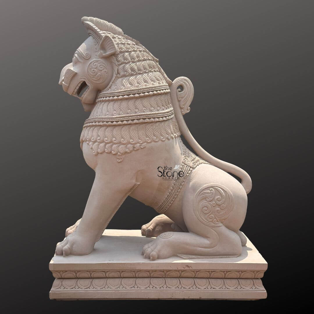 Traditional Stone Temple Lion Statue 7ft 1 A magnificent 7-foot traditional stone temple lion statue carved from off-white sandstone is presented in a majestic side profile against a dark plain background emphasizing its grandeur and intricate details. The statue depicts a powerful lion in a seated alert posture embodying strength guardianship and regal authority making it an iconic piece for temple entrances or grand architectural settings. The light natural hue of the sandstone allows the elaborate carvings to stand out vividly. The lion's features are highly stylized and ornamental typical of traditional temple art. Its mane is intricately carved with layers of textured patterns resembling scales or braided hair and its powerful neck is adorned with decorative bands. The lion's face seen in profile features prominent eyes a strong snout and an open mouth conveying a sense of watchful guardianship. Its muscular body is embellished with swirling motifs and decorative elements on its shoulders and hindquarters. The tail curls elegantly along its back terminating in an ornamental flourish. The entire sculpture rests upon a robust multi-tiered base also adorned with intricate patterns providing a solid foundation and enhancing its imposing presence. This 7-foot off-white sandstone Traditional Stone Temple Lion Statue is a profound representation of power protection and divine authority perfectly suited for the entrance of a temple or a significant architectural site. The exceptional craftsmanship in sandstone not only makes it a visually striking piece but also imbues it with deep cultural and religious significance. This exquisitely detailed statue serves as a commanding sentinel radiating strength and an ancient spiritual presence embodying centuries of artistic tradition and architectural grandeur.
