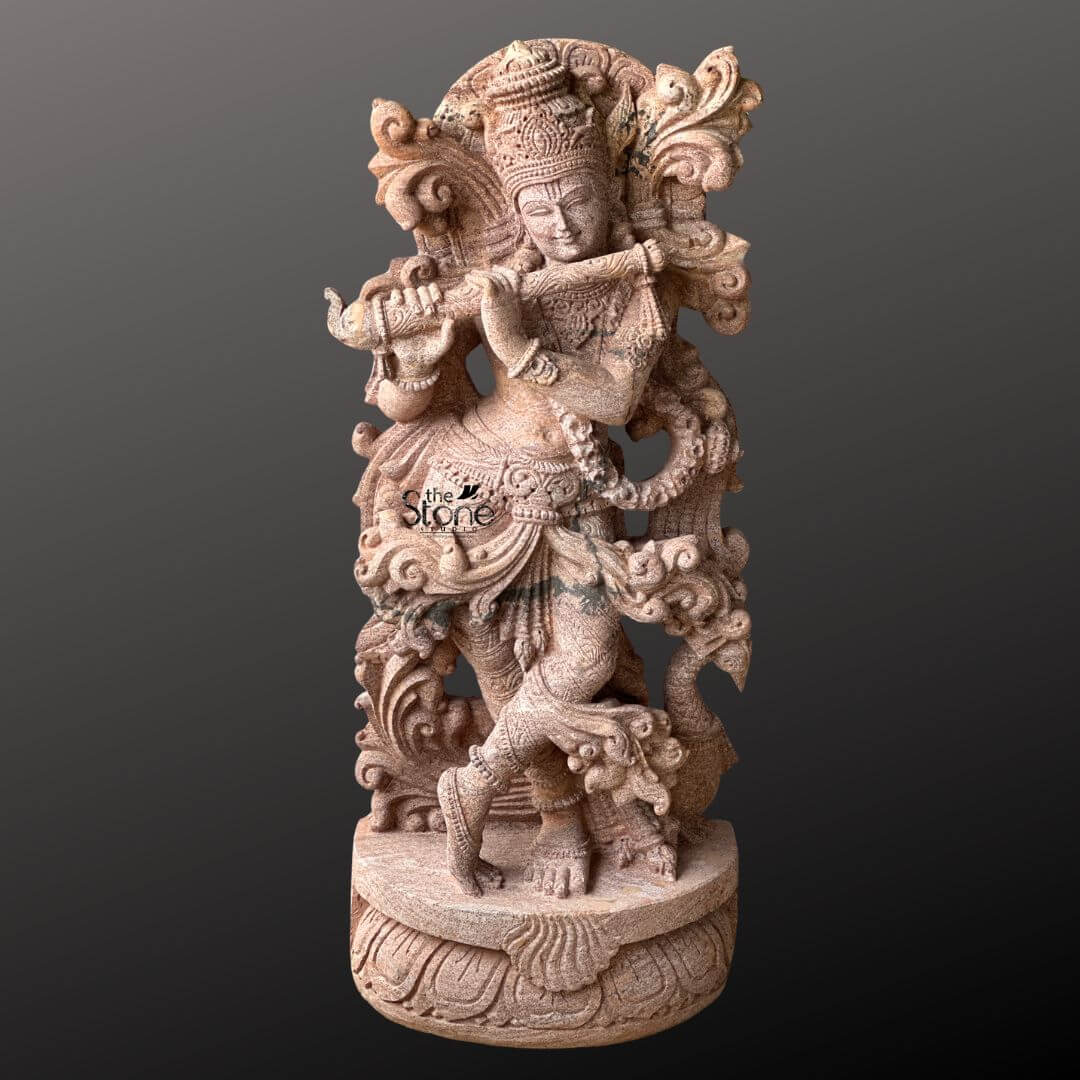 Standing Krishna Stone Statue with Flute 3.5ft 9 A magnificent 3.5-foot Tribhanga Krishna stone statue meticulously carved from sandstone stands elegantly against a deep contrasting background. Lord Krishna is depicted in his iconic Tribhanga pose a graceful and artistic posture characterized by a sway in his body as he plays his divine flute. His left leg is crossed delicately in front of his right creating a sense of dynamic movement and artistic balance while his hands are positioned to hold the flute evoking the enchanting melodies for which he is celebrated. The sandstone sculpture is a testament to exceptional craftsmanship featuring a wealth of intricate details that highlight its artistic and spiritual significance. Krishna is adorned with an elaborate crown exquisitely carved with patterns and possibly featuring the revered peacock feather a quintessential symbol of his divine persona. His form is richly embellished with finely carved jewelry including multiple necklaces armlets a decorative waistband and anklets all rendered with precision in the warm-toned stone. The flowing drapery of his dhoti and the intricately sculpted sashes appear to swirl around him adding to the statue's lifelike quality. Behind Krishna an ornate swirling motif possibly representing divine foliage or celestial clouds frames his upper body enhancing his majestic presence. This 3.5-foot sandstone Tribhanga Krishna statue is an ideal focal point for an article specifically highlighting this classic artistic pose. The warm earthy tones of the sandstone naturally enhance the intricate carvings and the spiritual aura of the deity. The skilled craftsmanship evident in every curve adornment and expressive element makes this statue a truly captivating and culturally significant piece embodying the charm and divine essence of Lord Krishna in a timeless and artistic form perfectly showcasing the beauty of the Tribhanga pose.
