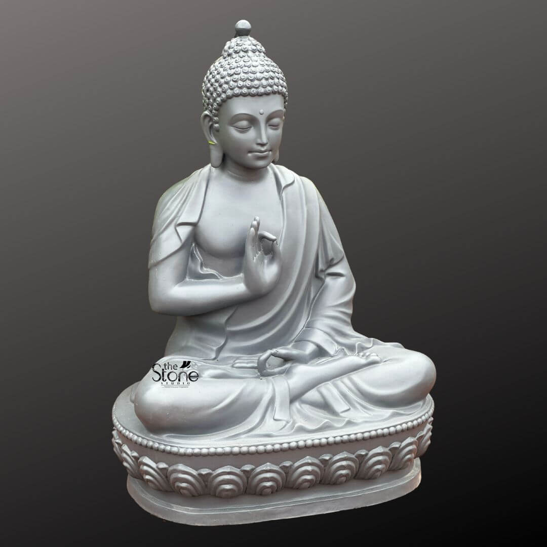 Seated Buddha Statue in Vitarka Mudra 3.5ft 6 A serene 3.5-foot Buddha Fibre statue resting gracefully on an ornate lotus pedestal is depicted against a muted dark grey background. The statue portrays Buddha in a meditative seated posture specifically the full lotus position symbolizing profound concentration and spiritual enlightenment. His right hand is raised in the Vitarka Mudra forming a circle with the thumb and index finger while the other fingers are extended signifying the transmission of teaching and intellectual discourse. His left hand is gently placed in his lap palm upwards representing meditation and receptivity. The statue boasts a uniform light grey finish which lends it a modern yet timeless aesthetic allowing the intricate details of the carving to stand out. The Buddha's facial features are exquisitely carved conveying a deep sense of peace and wisdom. His eyes are gently closed or cast downwards suggesting introspection and inner calm. A subtle smile plays on his lips and his elongated earlobes characteristic of Buddhist iconography recall his life as a prince who renounced material wealth. His head is crowned with tightly coiled hair leading up to the ushnisha the symbolic protuberance signifying his awakened mind and superior spiritual knowledge. The drapery of his robes is sculpted with graceful flowing lines that convey the softness and texture of fabric contributing to the statue's overall lifelike quality and elegant form. The most prominent feature connecting to the article's title is the elaborate double-lotus pedestal upon which Buddha is seated. Each petal is meticulously carved creating a beautiful and symbolic foundation that elevates the figure. The lotus is a powerful symbol in Buddhism representing purity spiritual growth and enlightenment emerging from defilement. This 3.5-foot Buddha Fibre statue with its significant presence and intricate design on its lotus pedestal makes a compelling statement piece ideal for inspiring tranquility and reflection in any indoor or outdoor setting perfectly aligning with an article focused on Buddha statues on lotus pedestals.