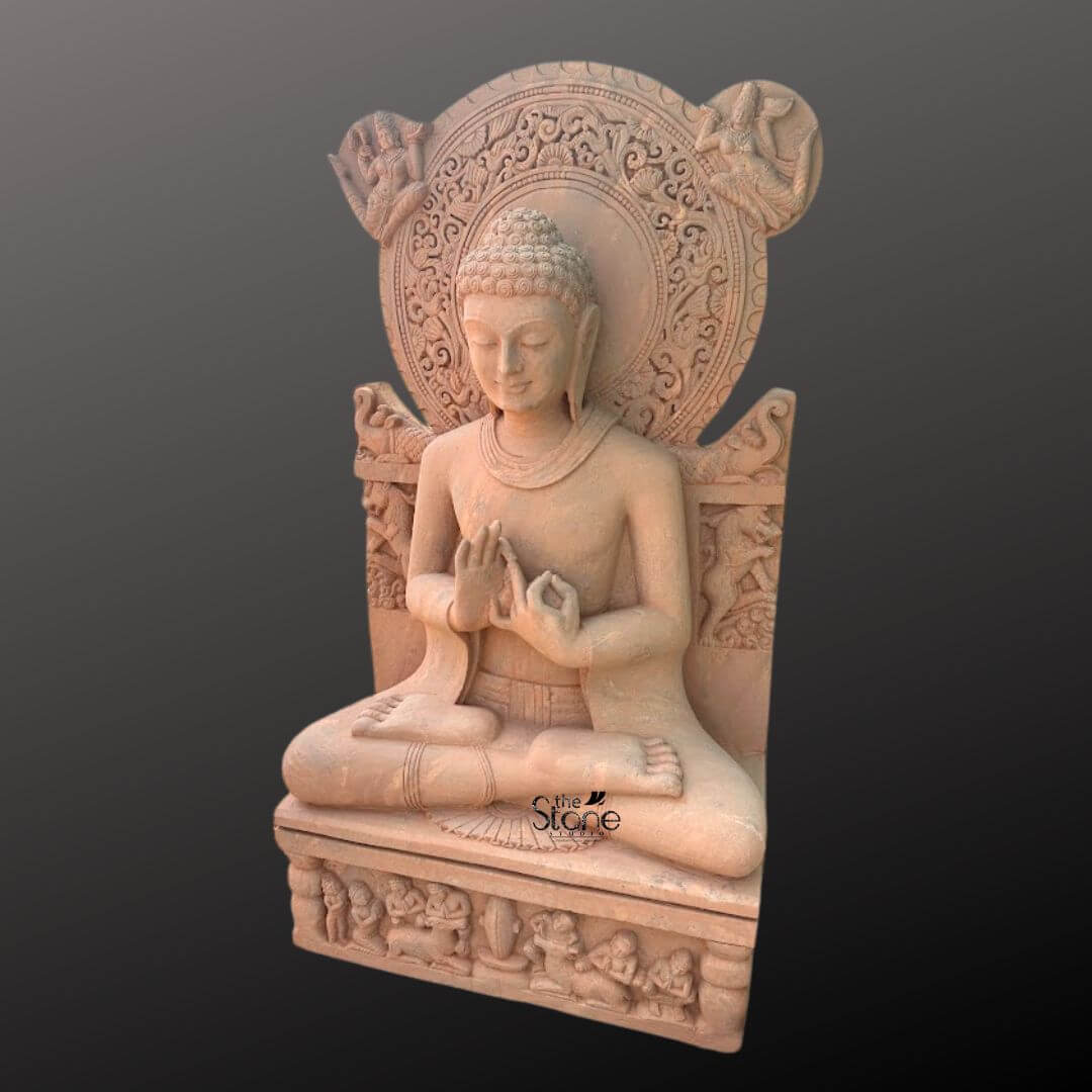 Sandstone Buddha Statue in Dharmachakra Mudra 5ft 5 A full-body studio photograph of a magnificent 5-foot Handstone Sandstone Buddha Statue presented in a three-quarter profile against a dark gray gradient background. The statue is masterfully carved from a warm reddish-brown sandstone exhibiting a rich natural texture. The Buddha is seated in the lotus position on a rectangular pedestal his legs crossed and feet visible embodying profound tranquility and meditative grace. His hands are held in the Dharmachakra Mudra the gesture of teaching and turning the wheel of Dharma with the thumb and index finger of both hands touching to form circles at chest level. The figure of the Buddha displays exquisite detail with a serene compassionate expression downcast eyes and a gentle smile. His hair is arranged in tight traditional curls, leading up to the ushnisha and he has elongated earlobes. He is draped in simple finely-pleated robes that fall naturally over his body showcasing the high level of artistry involved in this handcrafted piece. The smooth, yet tactile surface of the sandstone emphasizes the sculptural form and the care taken in its creation making it a stunning example of traditional stone carving.Behind the seated Buddha rises a highly ornate, intricately carved prabhamandala or halo. This circular aureole is adorned with elaborate relief patterns including stylized floral motifs celestial figures and mythical creatures adding to the statue's divine aura. The seat itself features carvings of elephants further enhancing the grandeur of the sculpture. The statue rests upon a robust pedestal which is also decorated with carved panels depicting rows of devotees and other figures in reverent postures. The overall composition highlights the monumental scale and spiritual presence of this significant handcrafted Buddha statue.