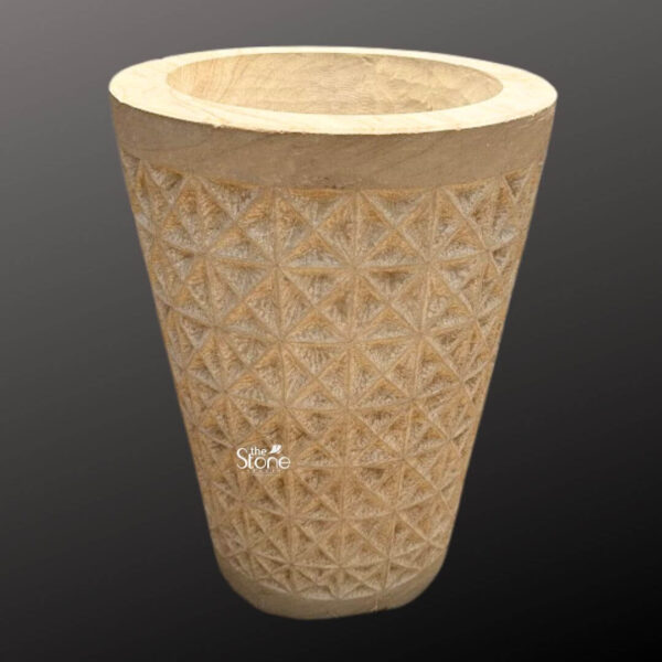 A full-view photograph of a magnificent 2-foot tall natural sandstone planter pot presented against a dark neutral gray gradient background. The planter is hand-carved from a single block of warm reddish-brown sandstone exhibiting a rich natural texture and tonal variations that highlight its stone origin. It is shaped in a classic slightly tapered cylindrical form with a thick smooth uncarved rim that provides a clean contrast to the body. The overall appearance conveys a sense of earthy elegance and robust craftsmanship. The central body of the sandstone planter pot is adorned with an intricate deeply carved geometric pattern. This pattern consists of a repeating tessellation of diamond and triangular shapes creating a textured three-dimensional facade that catches the light and adds visual depth. The precision of the carving demonstrates a high level of skill turning the functional object into a piece of sculptural art. The natural porosity of the sandstone is visible emphasizing its suitability for outdoor garden environments. This substantial stone planter pot standing at 2 feet is a versatile piece of garden decor. Its natural stone construction and timeless geometric design make it an ideal choice for showcasing large plants both indoors and outdoors. The planter's scale and intricate carvings make it a striking focal point for any patio deck or garden path seamlessly blending with natural landscapes while adding a touch of artisanal flair. The image clearly depicts the texture scale and design of the planter perfect for an article discussing natural stone garden elements.
