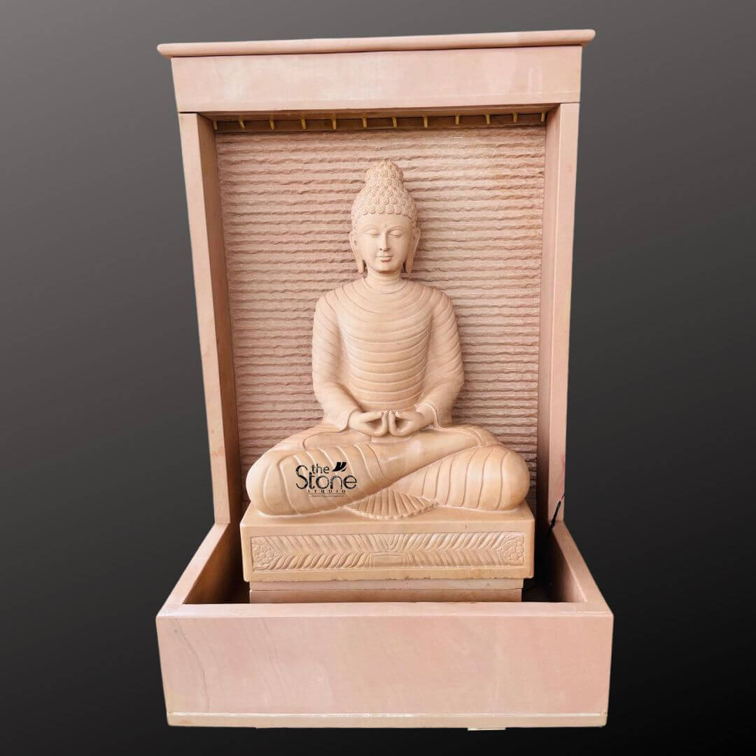 Outdoor Buddha Stone Water Fountain 4.5ft 1 A majestic five-foot-tall Buddha statue is the centerpiece of a sophisticated outdoor stone water fountai presented in a clean studio shot against a dark grey background. The entire fountain structure including the statue is hand-carved from a beautiful warm-toned sandstone exhibiting a natural textured porous surface that enhances its organic feel. The Buddha sits in a traditional meditative pose on a detailed lotus pedestal with hands resting in the lap in the dhyana mudra symbolizing deep contemplation. His facial expression is serene and compassionat with downcast eyes a gentle smile and tightly curled hair leading to a ushnisha all rendered with exquisite craftsmanship and flowing yet subtle carved folds of his robes. The statue is enclosed within a monolithic frame-like sandstone structure creating a stunning wall-fountain design. Water is subtly distributed to flow like a gentle curtain down the textured horizontally-ribbed back panel directly behind the Buddha pooling into the large monolithic rectangular basin at the base. The sound of the cascading water adds a tranquil multi-sensory dimension to the visual stillness of the statue. The warm earthy hue of the sandstone contrasts beautifully with the cool dark background making the statue pop and highlighting its intricate details and substantial presence. This five-foot Buddha fountain sandstone statue is an ideal illustration for an article discussing Outdoor Buddha Stone Water Fountains demonstrating how such a piece can transform a garden or patio into a peaceful sanctuary. Its large scale ensures it becomes a commanding focal point while the durable sandstone construction makes it suitable for enduring outdoor elements as a long-lasting garden ornament. The combination of sacred art with the gentle movement of water embodies a sense of harmony and spirituality perfect for creating a dedicated space for meditation reflection and aesthetic appreciation in any outdoor living area.