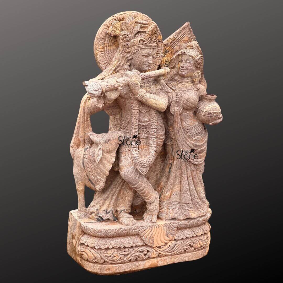 Radha Krishna Stone Statue with Cow 4ft 8 A magnificent 4-foot Premium Radha Krishna Sandstone Statue intricately carved stands gracefully against a dark gradient background radiating divine love and harmony. The statue carved from warm reddish-brown sandstone prominently showcases its premium craftsmanship depicting Lord Krishna and Radha in a loving standing pose. Krishna distinguished by his elaborate crown and serene expression holds a flute to his lips poised as if playing a melodious tune. Radha stands gracefully beside him adorned with a similar crown and traditional attire her gaze fixed on Krishna while she carries a pot of water or butter symbolizing her devotion and nurturing spirit. This highly detailed carving beautifully captures their divine romance and pastoral setting. The craftsmanship is exquisite with intricate details defining their elaborate crowns delicate jewelry and flowing traditional garments. The sandstone's prominent natural texture and subtle variations in color enhance the antique feel of the sculpture bringing out the tender expressions on their faces and the intricate patterns of their attire. A halo-like circular aureole with ornate patterns frames Krishna's head further emphasizing his divine presence. A small docile cow is subtly depicted near Krishna's feet symbolizing his role as a protector and caretaker of cattle adding to the pastoral charm. The exceptional detail and finish make this a premium piece suitable for prominent display. The entire ensemble rests on a multi-tiered intricately carved pedestal adorned with lotus petal designs and other traditional motifs providing a stable and dignified foundation. The depth and detail of the carving across the entire 4-foot statue are remarkable showcasing the artistry of the piece and the beauty of the natural sandstone. This Premium Radha Krishna Sandstone Statue is an exquisite example of religious artistry designed to bring blessings love and aesthetic beauty to any garden home, or temple making it an ideal focal point for devotion perfectly aligning with an article focusing on such charming and symbolically rich premium sandstone Radha Krishna statues for gardens.