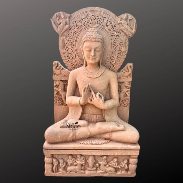 A full-body photograph of a magnificent 5-foot tall Sandstone Buddha Statue seated in the lotus position on an ornate pedestal. The statue rendered in a warm reddish-brown sandstone exhibits masterful craftsmanship with smooth flowing lines and intricate detailing. The Buddha is seated in the padmasana pose with both hands held in the Dharmachakra Mudra a gesture symbolizing the turning of the wheel of Dharma. The specific mudra is formed by the thumb and index finger of both hands touching to create circles with the left palm facing inwards and the right palm facing outwards. The Buddha's expression is one of profound tranquility and serenity with downcast eyes and a gentle smile. He has the traditional curled hair ushnisha and elongated earlobes. The statue wears simple flowing robes that drape naturally over his body. Behind the Buddha stands a highly detailed carved sandstone prabhamandala that arches over his head featuring elaborate patterns celestial figures, and mythical creatures. This detailed halo emphasizes his divine nature and is a key element in identifying the statue's iconographic significance within Buddhist art. The statue is supported by a substantial rectangular pedestal which is equally detailed with rows of carved figures including devotees musicians and possibly bodhisattvas paying homage to the central figure. The entire composition is set against a clean neutral dark gray background ensuring the focus remains entirely on the intricate details and spiritual presence of the 5-foot Sandstone Buddha statue in the Dharmachakra Mudra. The scale and craftsmanship are evident making this a significant piece for any collection or study of Buddhist iconography.