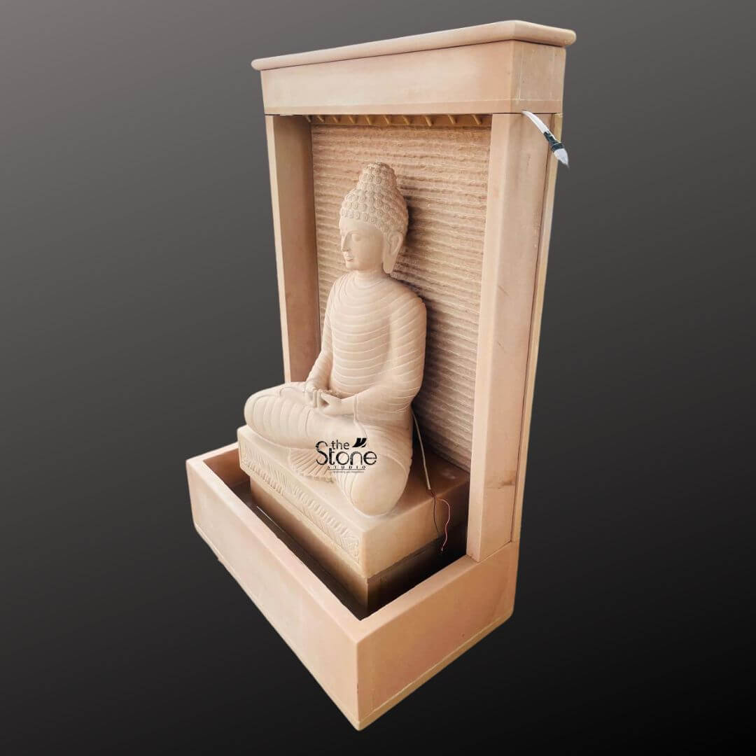 Outdoor Buddha Stone Water Fountain 4.5ft 8 A magnificent four-and-a-half-foot tall Buddha statue sits in a traditional meditative pose serving as the serene centerpiece of a contemporary off-white sandstone water feature. The entire structure including the statue and the monolithic frame that encloses it is hand-carved from beautiful light beige-to-grey sandstone exhibiting a natural textured porous surface that enhances its organic earthy feel. The Buddha is depicted in a seated meditative pose on a raised pedestal with legs crossed in a full lotus position and hands resting in the lap in the dhyana mudra of deep contemplation. His face exhibits a calm compassionate expression with downcast eyes a gentle smile and tightly curled hair leading to a cranial ushnisha all rendered with precise and reverent craftsmanship. The statue is integrated into a modern frame-like sandstone water wall structure. Water is subtly distributed from the top designed to flow like a gentle curtain down the textured horizontally-ribbed back panel directly behind the Buddha creating a soothing cascading effect. The water collects in the large rectangular basin at the base which is also made of the same off-white sandstone. The sound of the flowing water adds a tranquil multi-sensory dimension to the visual stillness of the statue creating a peaceful and meditative atmosphere. This four-and-a-half-foot Buddha Fountain Off White Sandstone Statue is an ideal illustration for an article discussing Sandstone Buddha Water Features demonstrating how such a piece can transform an indoor or outdoor space into a peaceful sanctuary. Its substantial scale ensures it functions as a commanding focal point while the durable sandstone construction makes it suitable for enduring elements as a long-lasting garden or patio ornament. The combination of traditional sacred art with the gentle movement of water embodies a sense of harmony spirituality and aesthetic beauty perfect for creating a dedicated space for meditation reflection and aesthetic appreciation in any living area. The detailed carving and harmonious integration of elements highlight its value as both a decorative and a meaningful addition to a modern landscape.
