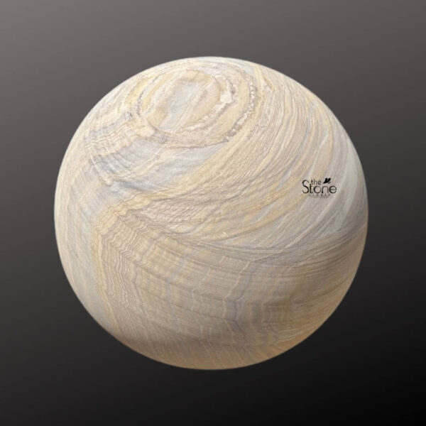 A perfectly spherical statue carved from natural sandstone is presented against a dark graduated studio background making the object the sole focus. The surface of the stone ball is polished smooth revealing a spectacular intricate pattern of swirling wavy geological striations. These natural sedimentary layers create a complex tapestry of colors blending bands of light cream warm beige, golden-tan and subtle grey which wrap dynamically around the spherical form highlighting its three-dimensional volume. The craftsmanship emphasizes the organic beauty and unique texture of the raw sandstone material. This substantial sandstone garden stone ball is designed as an elegant and durable piece of outdoor decor suitable for enhancing various landscape designs. Its smooth finish allows it to be easily integrated into different garden styles from modern minimalist settings to classic rock gardens or Japanese-inspired landscapes. The spherical shape represents unity and perfection while the earthy tones of the sandstone provide a warm natural contrast against green foliage and dark soil making it an ideal focal point for any garden or patio. The ball's natural appearance and size give it a commanding yet harmonious presence in an outdoor environment. It can be placed directly on the ground nestled among pebbles or plants or raised on a simple pedestal to serve as a decorative accent. The sandstone is naturally weather-resistant ensuring the intricate banding and smooth texture will endure the elements adding a touch of timeless artistry to the garden. This garden ball statue exemplifies how natural stone can be sculpted into simple elegant forms that bring sophistication to outdoor living spaces.