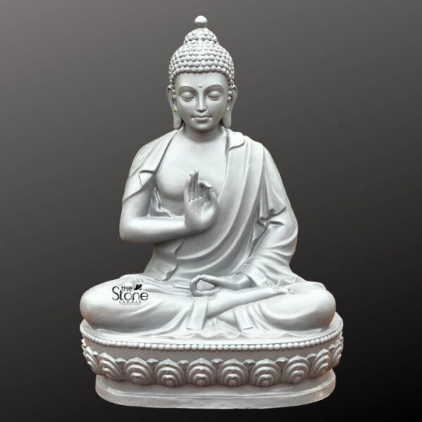 A striking 3.5-foot Seated Buddha Statue in Vitarka Mudra crafted from fiber is presented against a deep contrasting grey background. The statue depicts Buddha in a serene meditative posture seated in the full lotus position. His hands are arranged in the Vitarka Mudra the gesture of teaching and intellectual discussion the thumb and index finger of his right hand touch to form a circle while the other fingers are extended upwards and his left hand rests gently in his lap with the palm facing upwards. The statue's monochromatic light grey finish gives it a contemporary and elegant appearance emphasizing the contours and details of the sculpture. Buddha's face exudes tranquility with eyes gently downcast a faint smile and elongated earlobes indicative of his princely past. His head is topped with tightly coiled hair and the ushnisha the cranial bump symbolizing his spiritual wisdom and enlightenment. The draping of his robes is rendered with flowing lines creating soft folds that suggest the texture of fabric and contribute to the statue's graceful form. The fiber material allows for a smooth finish and precise detailing making the statue appear substantial yet refined. The Buddha sits upon a beautifully sculpted double-lotus pedestal with each petal intricately carved signifying purity and spiritual awakening. This 3.5-foot Buddha Fibre statue embodying the Vitarka Mudra is a powerful representation of Buddhist philosophy and a focal point for contemplation and teaching. Its impressive size and detailed craftsmanship make it an ideal piece for meditation spaces gardens or as a significant cultural accent in a home or public setting aligning perfectly with the article's focus on Seated Buddha Statues in this specific mudra.