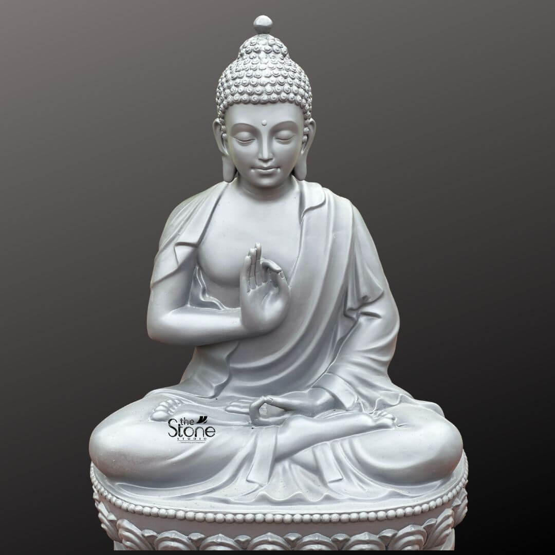 Seated Buddha Statue in Vitarka Mudra 3.5ft 2 A magnificent 3.5-foot Teaching Buddha Meditation Statue crafted from fiber is prominently displayed against a uniform dark grey background offering a sense of depth and focus. The statue depicts Buddha in a classic meditative posture seated in the full lotus position symbolizing deep concentration and spiritual enlightenment. His right hand is raised in the Vitarka Mudra forming a circle with the thumb and index finger while the other fingers are extended clearly conveying the act of teaching and intellectual discussion central to the article's theme. His left hand rests gently in his lap palm upwards signifying contemplation and receptivity. The statue's consistent light grey finish provides a contemporary and elegant aesthetic allowing the subtle contours and fine details of the sculpture to be clearly appreciated. The Buddha's face is carved with exceptional artistr radiating profound peace wisdom and the calm assurance of a teacher. His eyes are gently closed or downcast suggesting deep introspection and a calm state of mind characteristic of a meditating figure prepared to share insights. A subtle serene smile graces his lips and his elongated earlobes a traditional symbol in Buddhist iconography subtly reference his detachment from worldly possessions. His head is adorned with tightly coiled hair culminating in the ushnisha the symbolic cranial protuberance that signifies his supreme spiritual knowledge and enlightenment gained through meditation and now imparted through teaching. The flowing drapery of his robes is expertly rendered with soft folds and graceful lines conveying the lightness and texture of fabric further enhancing the statue's peaceful and elegant form. The Buddha is seated upon a beautifully sculpted double-lotus pedestal with each petal intricately carved symbolizing purity spiritual growth and the emergence of enlightenment from the mundane. This impressive 3.5-foot Buddha Fibre statue embodying profound spiritual meaning and artistic excellence is an ideal representation for a Teaching Buddha Meditation Statue. Its significant size and detailed craftsmanship make it a perfect centerpiece to inspire tranquility reflection and the pursuit of wisdom in any indoor or outdoor living space aligning perfectly with the article's theme of a meditating Buddha engaged in teaching.