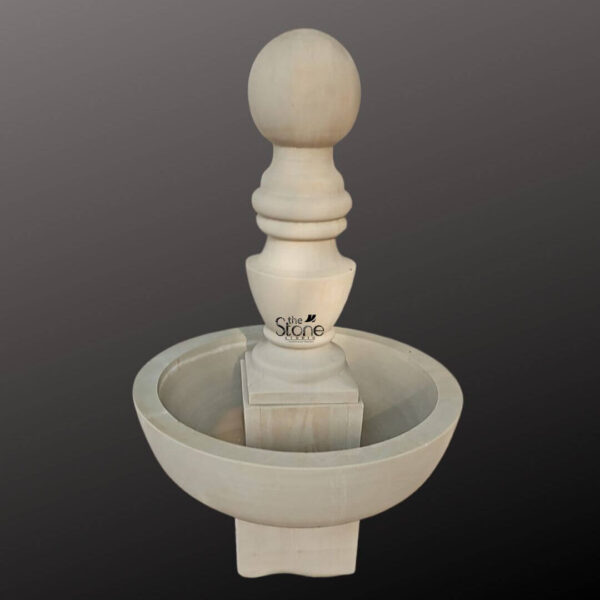 This is a centered eye-level photograph of a traditional tiered garden water fountain standing 54 inches tall and hand-carved from a warm light-colored natural sandstone. The fountain is composed of a large circular lower basin that catches the water with a thick sturdy pedestal rising from its center. This central pillar supports a smaller shallower upper basin creating a classic two-tier design. The stone has a finely textured matte finish that showcases the natural grain and artisanal craftsmanship of the sandstone material making it an elegant focal point for outdoor spaces. The central column features a series of decorative turned-stone mouldings just above the main basin transitioning into a smooth bulbous shape that culminates in a perfectly spherical finial at the very top. Water would flow from the apex of this finial cascading down the mouldings and into the upper basin before spilling over the rim into the larger lower reservoir. The design is symmetrical and balanced reflecting a timeless aesthetic that complements both classic and contemporary garden landscapes. The solid stone construction ensures durability for outdoor use. The fountain is presented against a seamless dark grey studio background that fades to black isolating the object and allowing its form and texture to be clearly visible. This presentation emphasizes the clean lines and sculptural quality of the piece without distractions. The lighting is soft and even illuminating the fountain from the front and slightly to the side which highlights the three-dimensional form and the subtle tactile quality of the sandstone surface. The overall composition conveys a sense of tranquility and high-quality craftsmanship inherent to this type of garden decor.