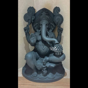A magnificent four-foot-tall Ganesha Fibre Statue stands as a divine centerpiece showcasing exceptional artistry and craftsmanship. The statue is rendered in a deep matte charcoal-grey finish mimicking the appearance of polished black stone while retaining the lightweight and durable properties of fibreglass. Ganesha is depicted in a traditional seated posture known as the Lalitasana pose with his right leg gracefully folded and his left leg slightly raised resting on a sturdy integrated lotus-petal-carved pedestal. The artisan has lavished attention on the intricate details from the elaborate crown and multiple necklaces adorning his form to the delicate folds of his flowing dhoti all highlighted by the statue’s uniform dark tone and subtle highlights from the focused indoor lighting. Ganesha is depicted with four arms, each holding a symbolic item: his upper right hand holds an ankusha his upper left holds a pasha and his lower right hand is in the Abhaya Mudra bestowing blessings. His lower left hand holds a modak resting in his lap. Behind the deity a large finely carved prabhavali is adorned with traditional patterns and culminates in a kirtimukha at the apex adding grandeur and spiritual significance to the composition. The statue’s expression is one of serene benevolence with large, defined eyes and a gently curved trunk holding the modak bowl. This four-foot Ganesha Fibre Statue is an ideal size for a prominent home shrine a temple hall or a garden sanctuary in Trichy where it would serve as a powerful focal point for devotion and cultural pride. The substantial height commands attention while the durable fibreglass material ensures its longevity making it a practical and revered choice for placement in various environments. The photograph against a plain textured wall emphasizes the statue's three-dimensional quality and the artisan's meticulous work on the decorative elements perfectly illustrating the grace and cultural richness that a well-crafted Ganesha statue brings to any space.