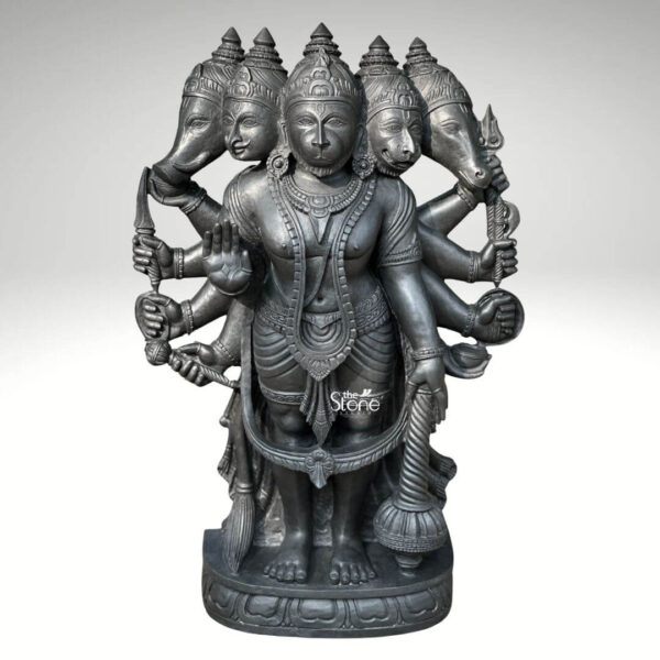 A full-view studio photograph set against a plain light grey background displays a magnificent 3.5-foot Panchamukha Anjaneya Swamy Stone Vigraham. This intricately hand-carved statue is made from a single block of deep dark blackstone, renowned for its durability and fine grain. The statue depicts the five-faced form of Lord Hanuman known as Panchamukhi Hanuman standing firmly on a multi-tiered ornate circular base. The central face is that of Hanuman himself looking forward with a serene protective expression adorned with traditional jewelry and a crown. Radiating outwards from the central head are four other divine faces: to the east the boar face to the south the lion face to the west the eagle face and to the north, the horse face. The statue is multi-armed totaling ten arms that hold various divine attributes each rendered with exquisite detail. The main central right hand is raised in the Abhaya mudra while the main central left hand holds a mace that rests on the base. The other eight hands hold a conch discus swor shield noose hook a mountain and a vessel. The deity is adorned with elaborate traditional South Indian carvings of kiritamukuta necklaces armlets wristlets, a sacred thread and a detailed dhoti all chiseled with precision into the dark stone. The fine texture of the blackstone enhances the depth and shadow of the carvings highlighting the complex iconography of this formidable yet benevolent form of Hanuman. This Panchamukha Anjaneya Swamy Stone Vigraham is an exceptional example of traditional Indian temple sculpture suitable for sanctum placement or as a grand focal point in a home shrine or spiritual space. The 3.5-foot height makes it a commanding presence embodying the combined power of the five deities represented by the faces. The blackstone material gives the statue a timeless ancient feel ensuring it will be a cherished piece for generations. The statue's detailed iconography from the expressions on the five faces to the specific items held in the ten hands makes it a significant subject for study and devotion. The expert craftsmanship transforms the raw stone into a vibrant sacred form.